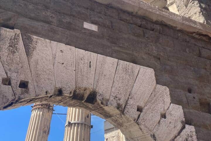 A Roman stone arch and two fluted marble columns of the Imperial Fora photographed from directly beneath